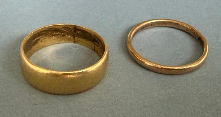 Twee ringen: een gouden met een brede band en een dunnere koperkleurige ring.